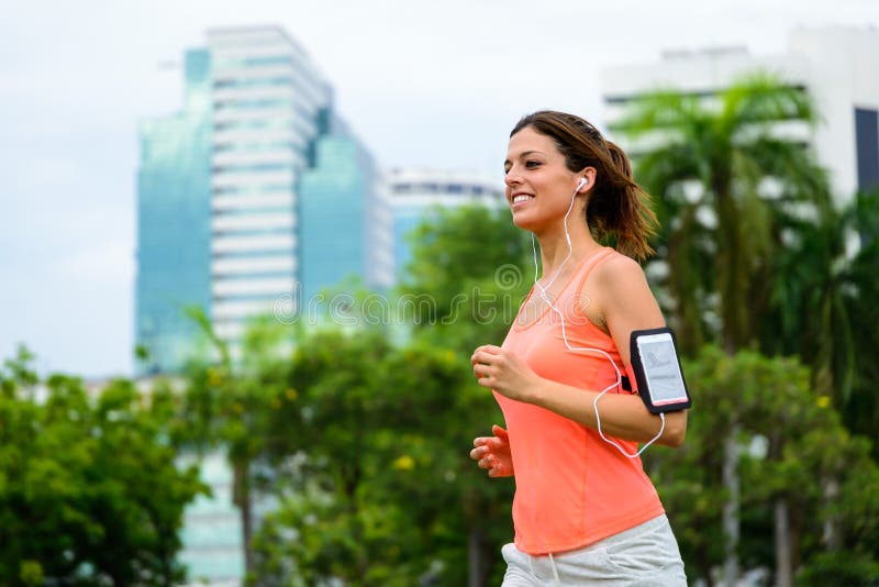 Happy fitness woman running at city park