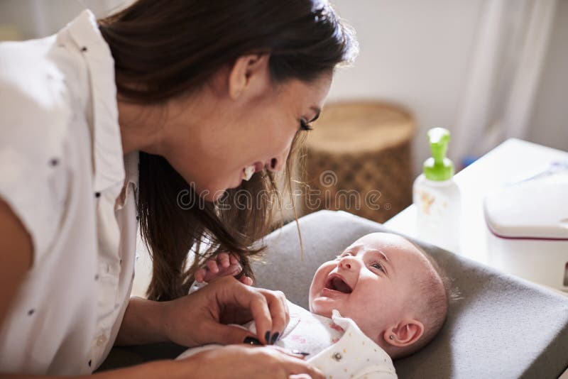 Happy four month old baby boy lying on changing table looking up at his mum, close up