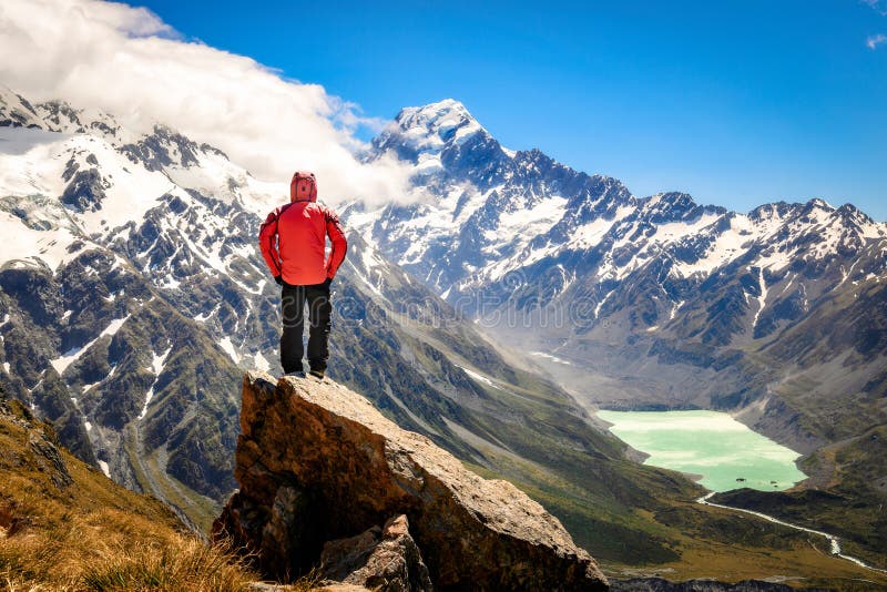 Happy free tourist man standing outstretched up looking at river and mountains landscape from Mueller Hut, MT. Cook - New Zealand