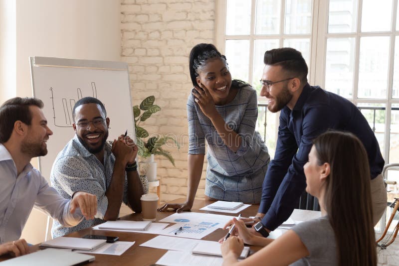 Happy friendly multiracial team laughing working together at corporate briefing