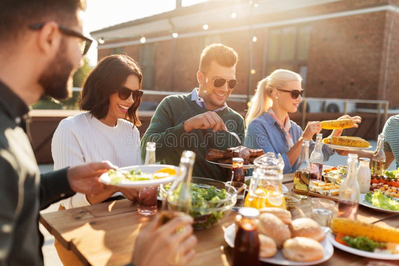 Happy friends eating at barbecue party on rooftop stock image Happy friends eating at barbecue party on rooftop stock image