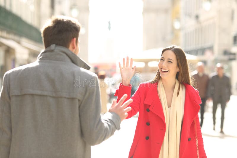 Two happy friends meeting and greeting in the street of a big city