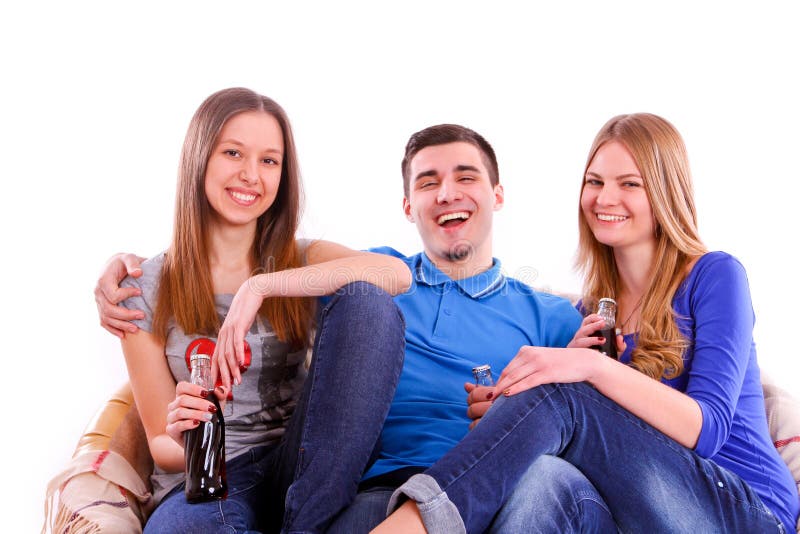 happy friends sitting on a sofa and drinking soda