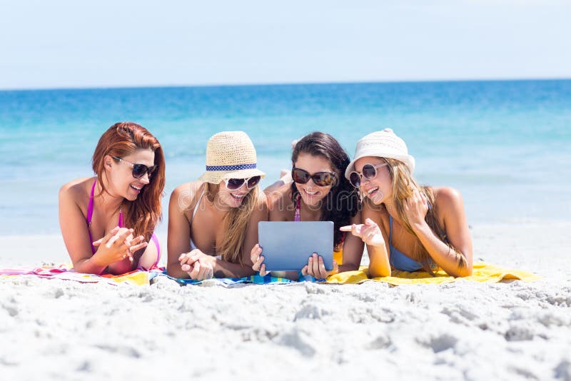 Felice amici di occhiali da sole e l'utilizzo di tablet in spiaggia.