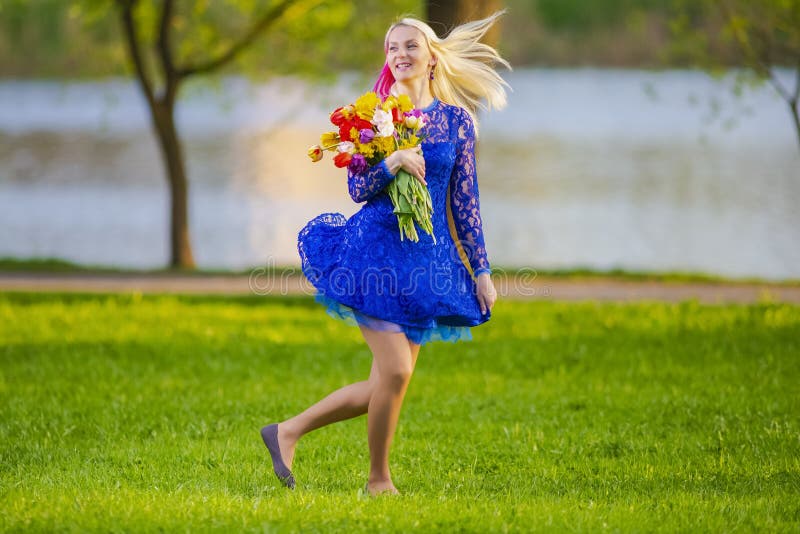 Happy and Funny Caucasian Blond Girl with Bunch of Tulips Running Against Nature Background