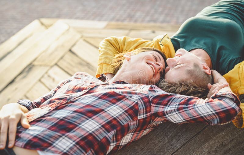 Happy gay couple lying on a bench looking each other - Young lesbian women having a tender romantic moment outdoor stock images Happy gay couple lying on a bench looking each other - Young lesbian women having a tender romantic moment outdoor stock images