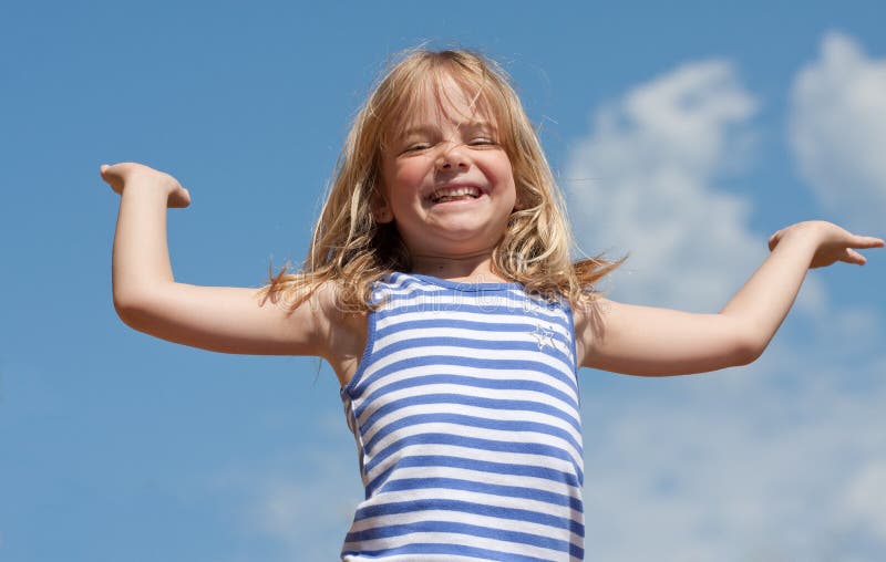 Happy girl with arms raised against blue sky background. Happy girl with arms raised against blue sky background.