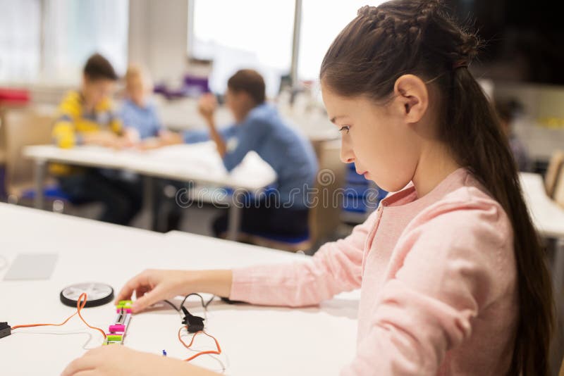 Happy girl building robot at robotics school
