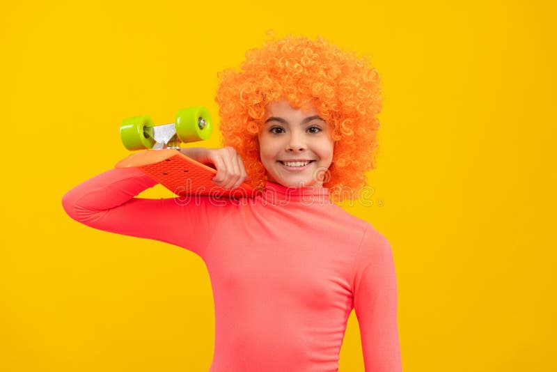 Happy girl child with orange hair in pink poloneck smile holding penny board, pennyboard stock images