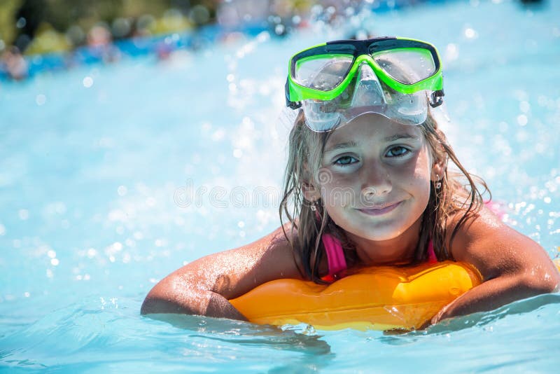 Happy girl child playing in the pool on a sunny day. Cute little girl enjoying holiday vacation