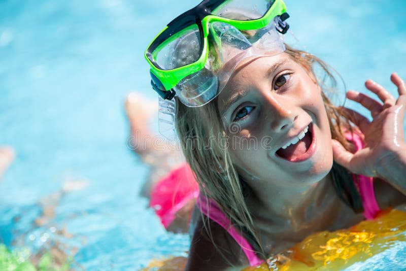 Happy girl child playing in the pool on a sunny day. Cute little girl enjoying holiday vacation