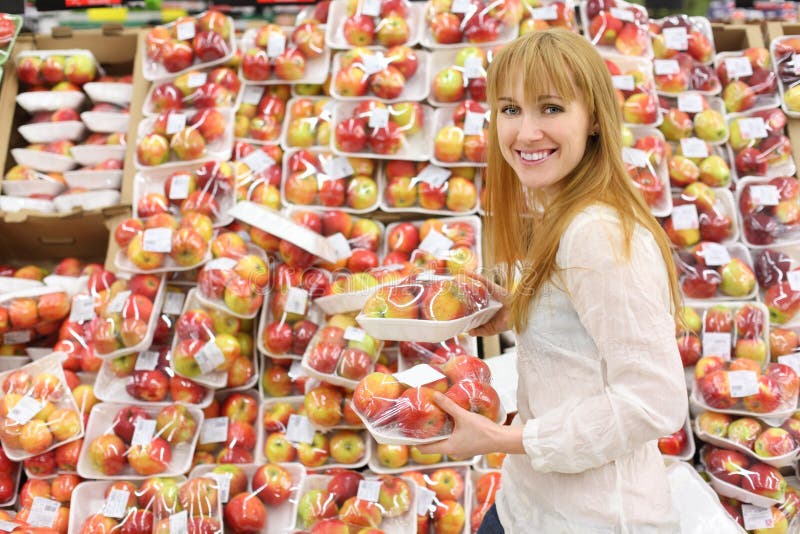 Happy girl chooses packed apples in store stock photography Happy girl chooses packed apples in store stock photography