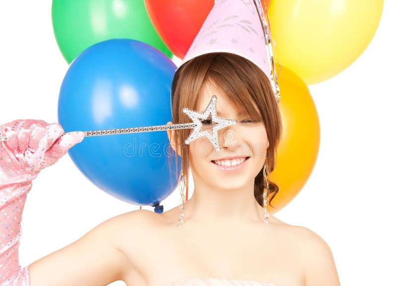 Happy girl with colorful balloons in party cap and magic stick