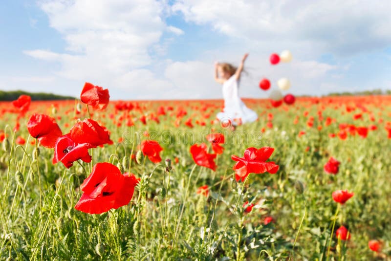 Happy girl with colorful balloons in poppies