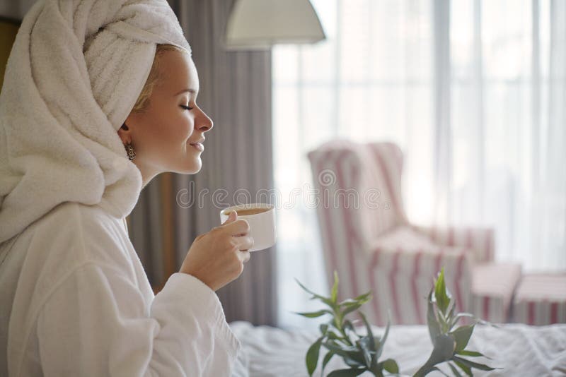 Happy Girl with a Cup of Coffee. Home Style Relaxation Woman Wearing Bathrobe and Towel after Shower. Spa Good Morning