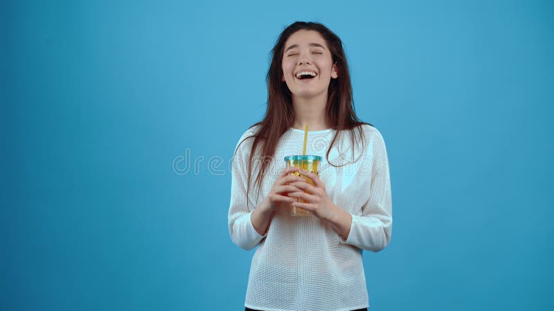 The happy girl drinks from her glass of juice with the straw, breathes contentedly and happily drinks on. Asian with