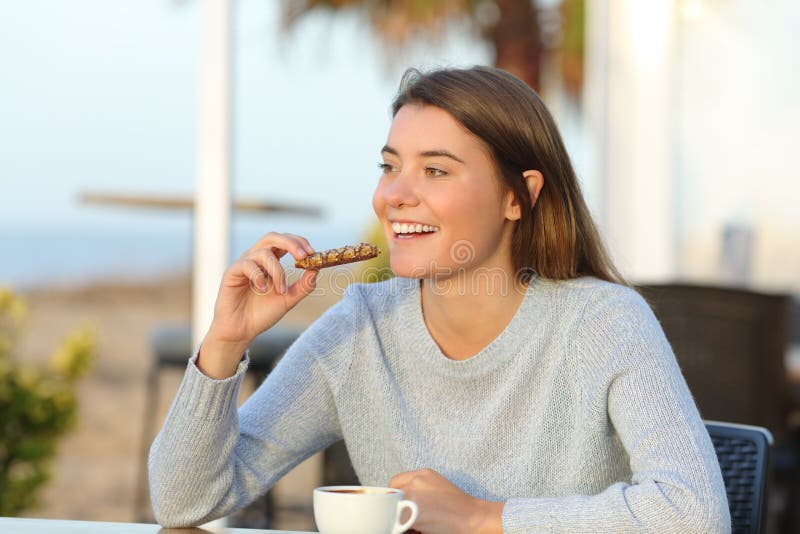Happy girl eating a snack in a cafe terrace royalty free stock photo Happy girl eating a snack in a cafe terrace royalty free stock photo