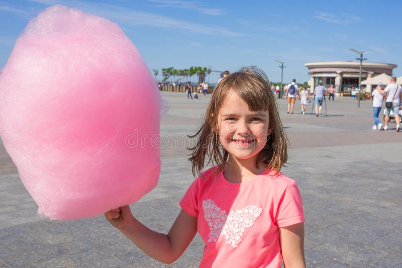 Happy girl holding cotton candy in an amusement park. Children