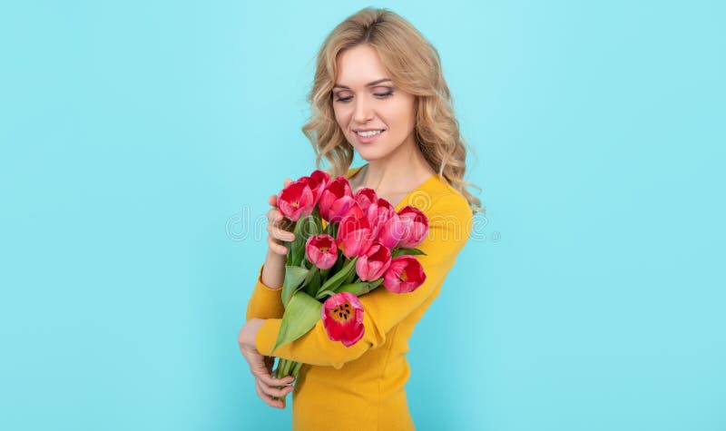 happy girl holding spring tulip flowers on blue background stock photo