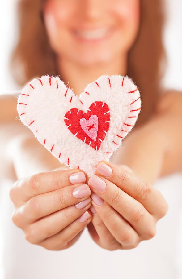 Happy girl in love. Picture of a small white heart in hands, female holds handmade sewn soft toy, macro, shallow dof, woman with Valentine gift, happy girl stock photography Happy girl in love. Picture of a small white heart in hands, female holds handmade sewn soft toy, macro, shallow dof, woman with Valentine gift, happy girl stock photography