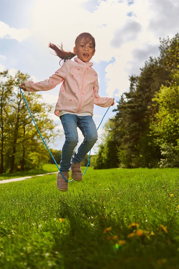 Happy girl in the rope jumping on a meadow in the summer during the holidays. Happy girl in the rope jumping on a meadow in the summer during the holidays