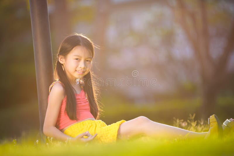 Happy girl sitting on grass in garden