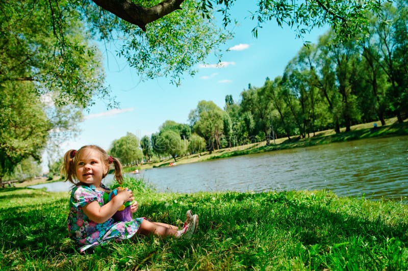 Happy girl sitting on river bank