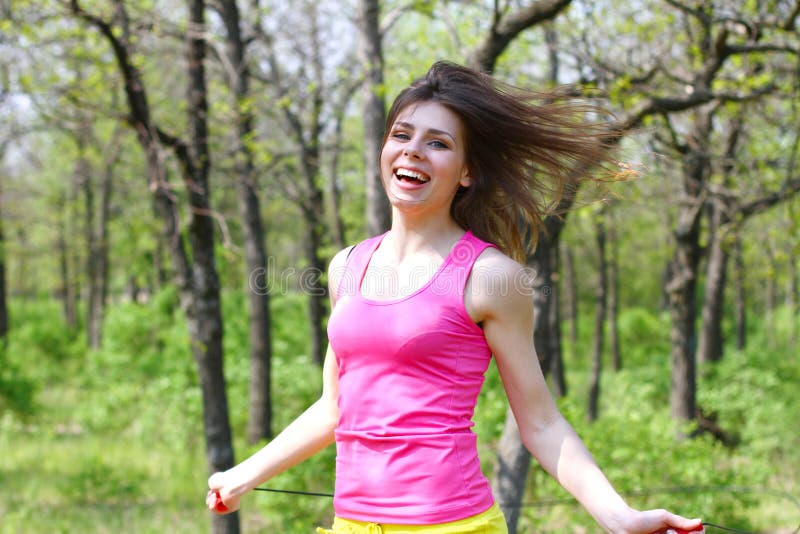 Happy girl with a skipping rope in a summer park