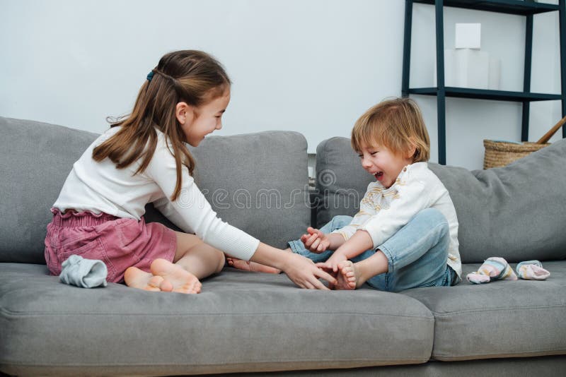 Happy girl tickling boy& x27;s foot, they both heartedly laugh.