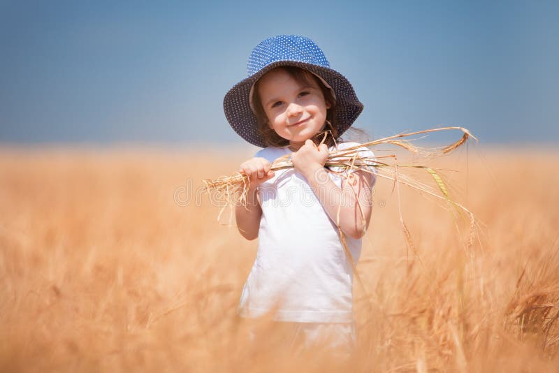 Happy girl walking in golden wheat, enjoying the life in the field. Nature beauty, blue sky and field of wheat. Family outdoor royalty free stock photography Happy girl walking in golden wheat, enjoying the life in the field. Nature beauty, blue sky and field of wheat. Family outdoor royalty free stock photography