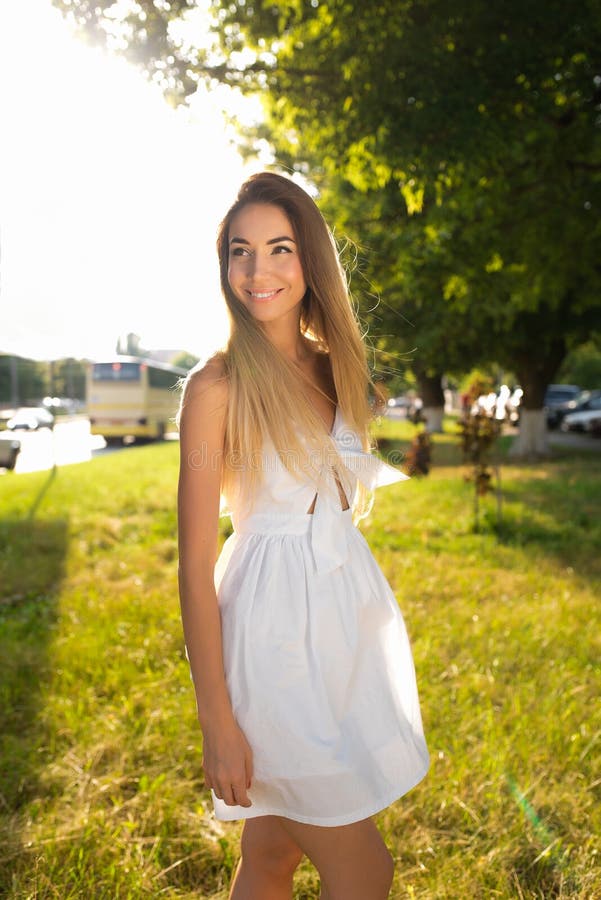 Happy girl walking in the summer in park. White dress long hair. Emotions of joy fun outdoor recreation. Concept walk