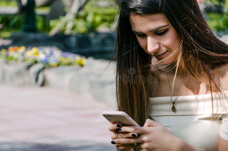 Happy girl watching media in a smartphone sitting on a bench of a park stock photos Happy girl watching media in a smartphone sitting on a bench of a park stock photos