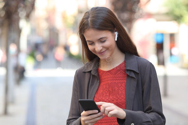 Happy girl wearing earbuds listening to music on phone