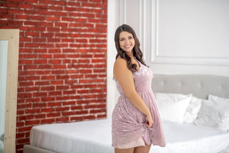 Young plus-size woman in a pink dress looking flirt and positive