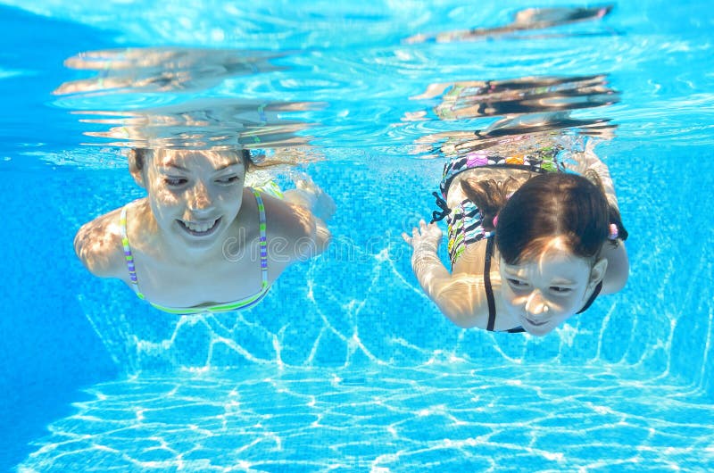 Happy girls swim underwater in pool