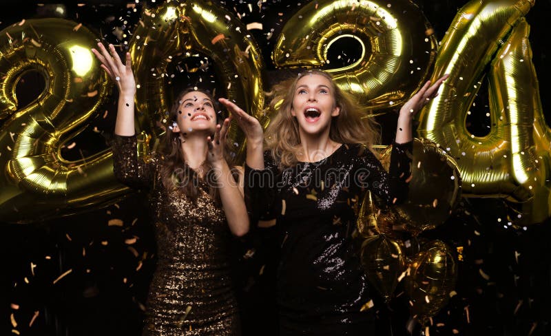 Happy gorgeous girls in stylish sexy party dresses holding gold 2024 balloons, having fun at New Year& x27;s Eve Party.