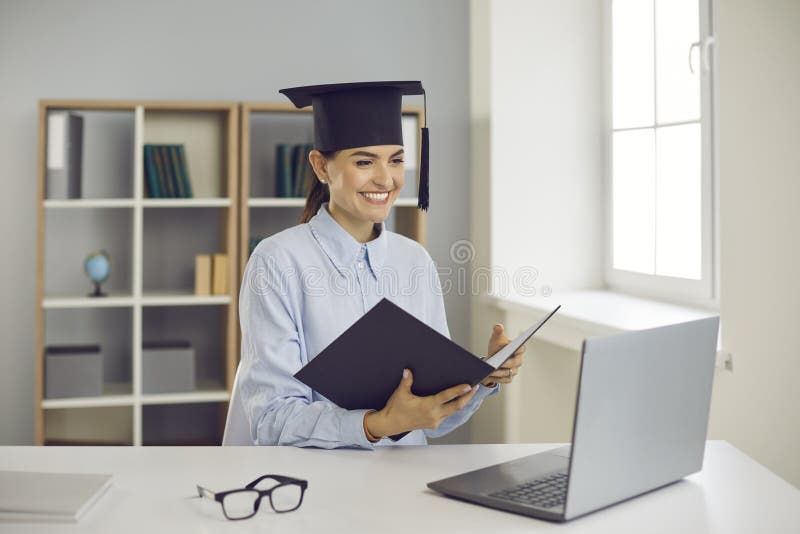 Happy graduate sitting at laptop computer and presenting her thesis remotely via video call