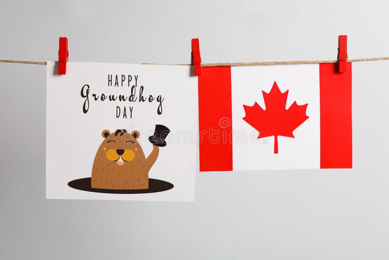 Happy Groundhog Day greeting card and Canada flag hanging on light background