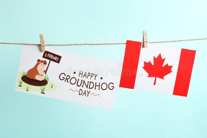 Happy Groundhog Day greeting card and Canada flag hanging on turquoise background