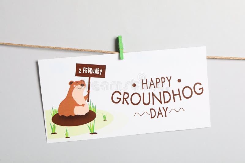 Happy Groundhog Day greeting card hanging on light background