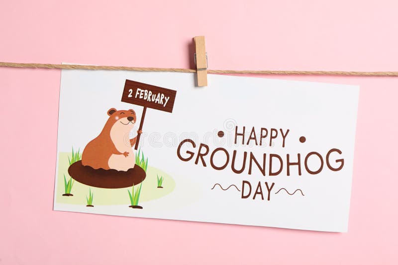Happy Groundhog Day greeting card hanging on pink background