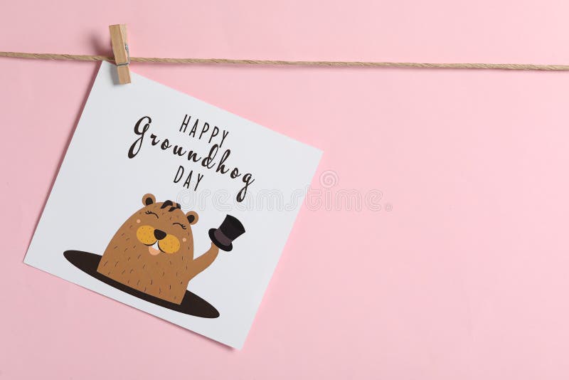 Happy Groundhog Day greeting card hanging on pink background, space for text