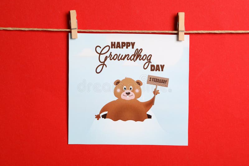 Happy Groundhog Day greeting card hanging on red background