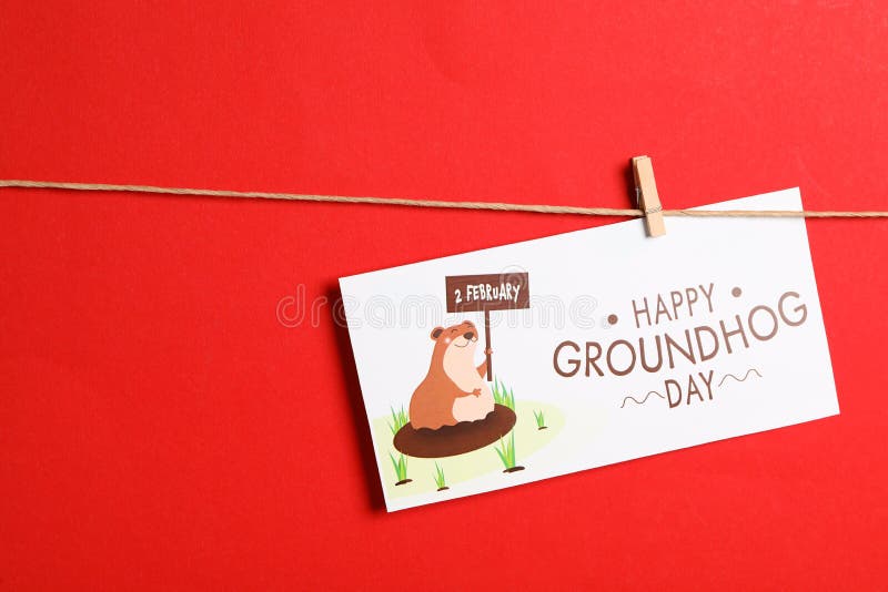 Happy Groundhog Day greeting card hanging on red background, space for text