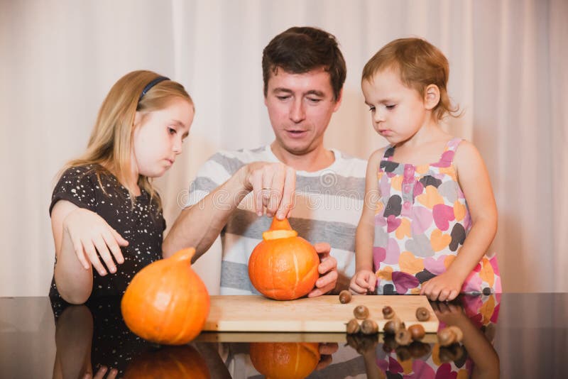 Happy halloween. Father and two daughters carving pumpkin for Halloween at home. Happy family stock photography Happy halloween. Father and two daughters carving pumpkin for Halloween at home. Happy family stock photography