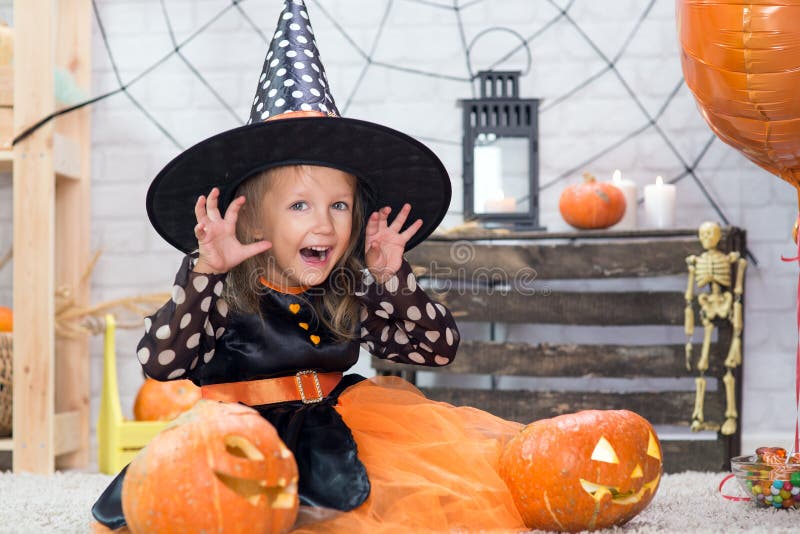 Happy Halloween. A little beautiful girl in a witch costume celebrates a home in an interior stock images Happy Halloween. A little beautiful girl in a witch costume celebrates a home in an interior stock images