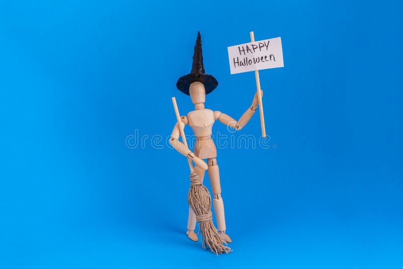 Happy Halloween sign held by jointed manikin dressed bin witches costume on blue background stock image Happy Halloween sign held by jointed manikin dressed bin witches costume on blue background stock image