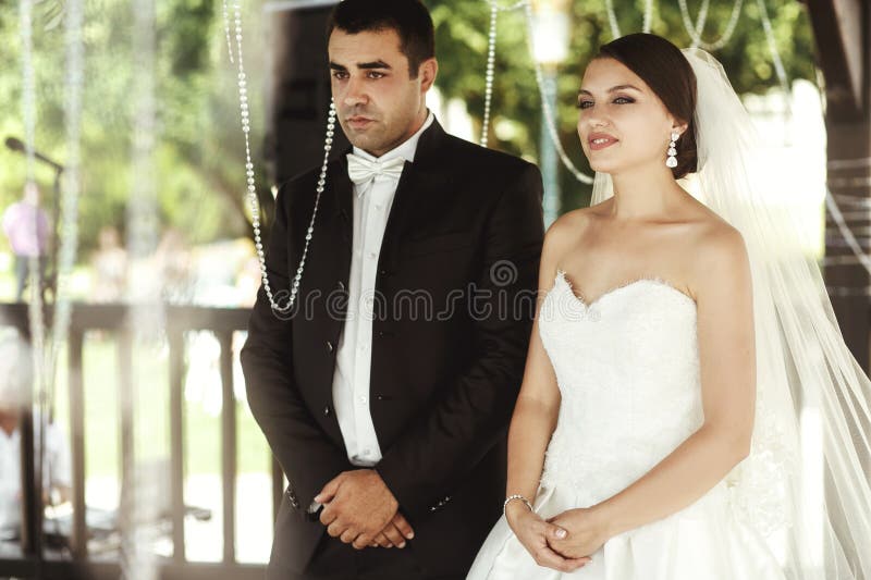 Happy handsome groom and beautiful bride in white dress in wedding arbor at ceremony royalty free stock images Happy handsome groom and beautiful bride in white dress in wedding arbor at ceremony royalty free stock images