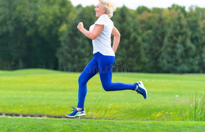 Happy healthy woman running through a park