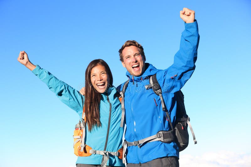 Happy hiking couple cheering in winning success concept. Young women and men hiker holding around eachother elated and cheerful with arms raised in the sky. Asian girl and Caucasian male hikers. Top smiling cheerful stock images, royalty-free photos and pictures